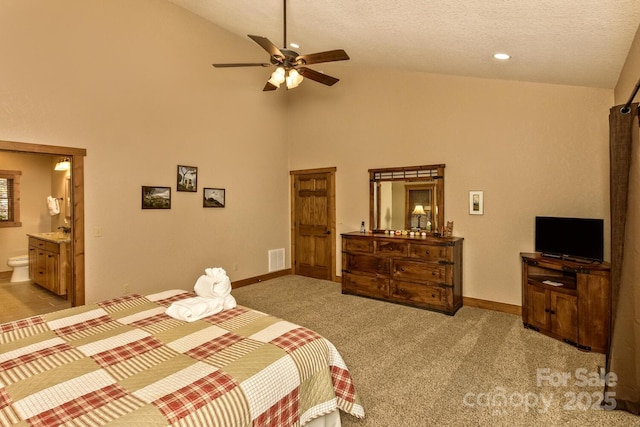 carpeted bedroom with ensuite bath, visible vents, a textured ceiling, and baseboards