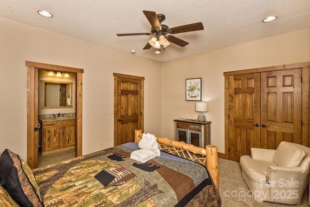 carpeted bedroom featuring a sink, a textured ceiling, ensuite bath, recessed lighting, and ceiling fan