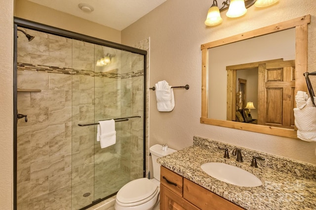 full bathroom with a stall shower, toilet, vanity, and a textured wall