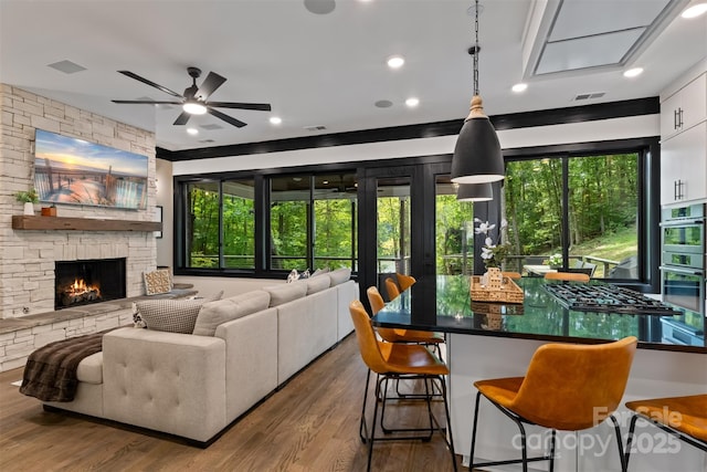 living room with visible vents, a fireplace, ceiling fan, and wood finished floors