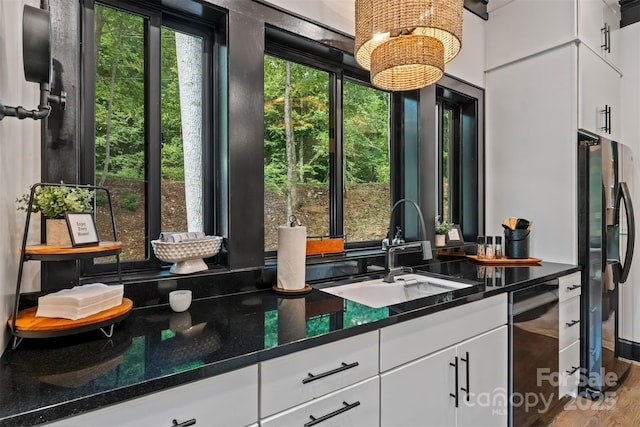 kitchen featuring a sink, black fridge with ice dispenser, wood finished floors, white cabinets, and dishwashing machine