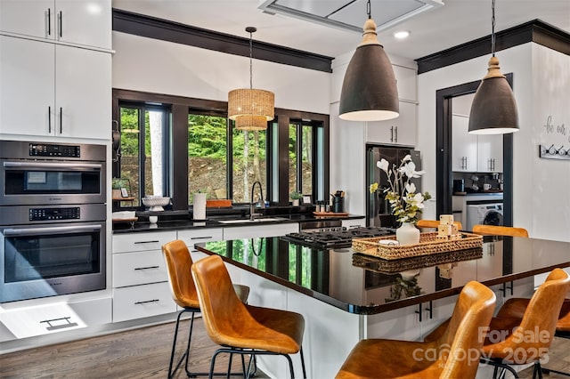 kitchen featuring a sink, a kitchen breakfast bar, double oven, and freestanding refrigerator