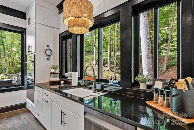 kitchen featuring a sink, dark countertops, dishwasher, and a healthy amount of sunlight