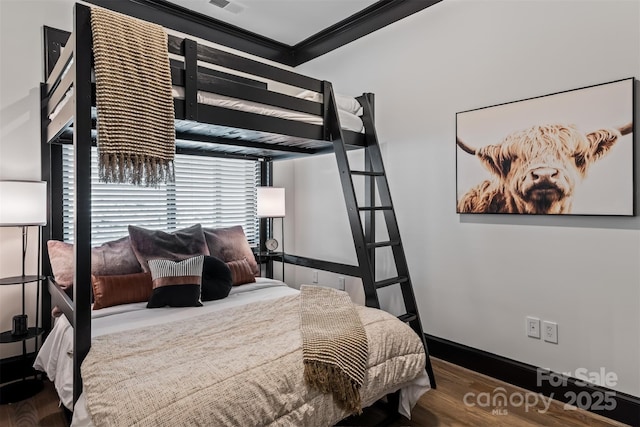 bedroom featuring visible vents, crown molding, baseboards, and wood finished floors