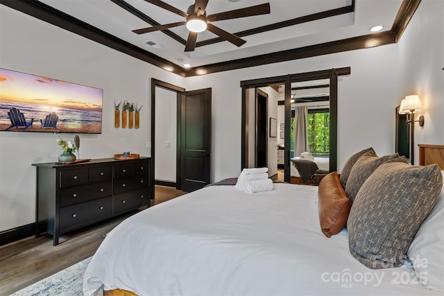 bedroom with visible vents, a raised ceiling, ornamental molding, wood finished floors, and baseboards