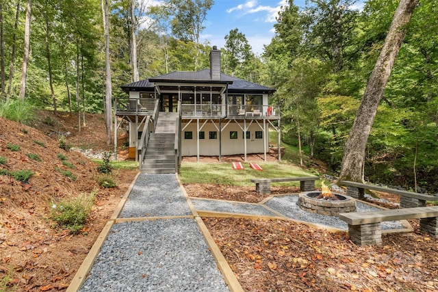 chalet / cabin featuring stairway, an outdoor fire pit, metal roof, a chimney, and a deck