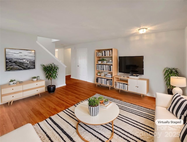 living room with stairway, wood finished floors, and baseboards