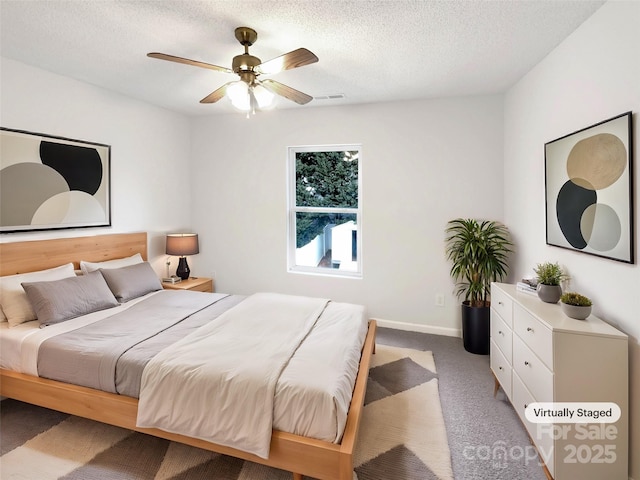 carpeted bedroom with baseboards, a ceiling fan, visible vents, and a textured ceiling