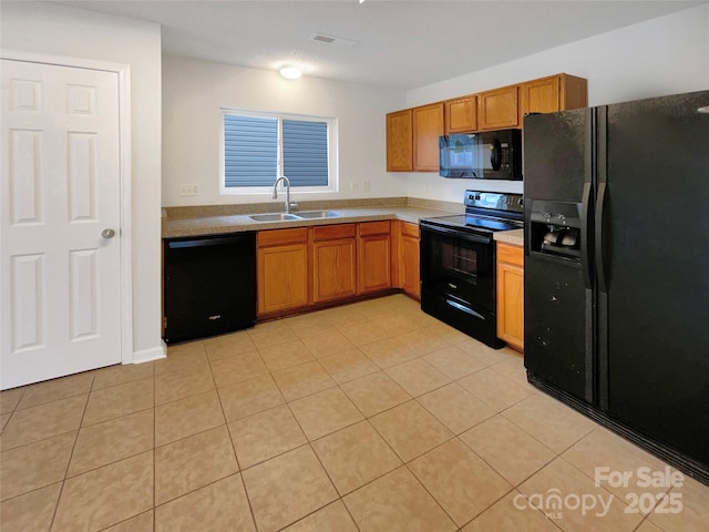 kitchen with visible vents, brown cabinets, black appliances, a sink, and light countertops