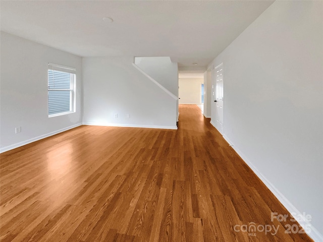 unfurnished living room with baseboards and wood finished floors