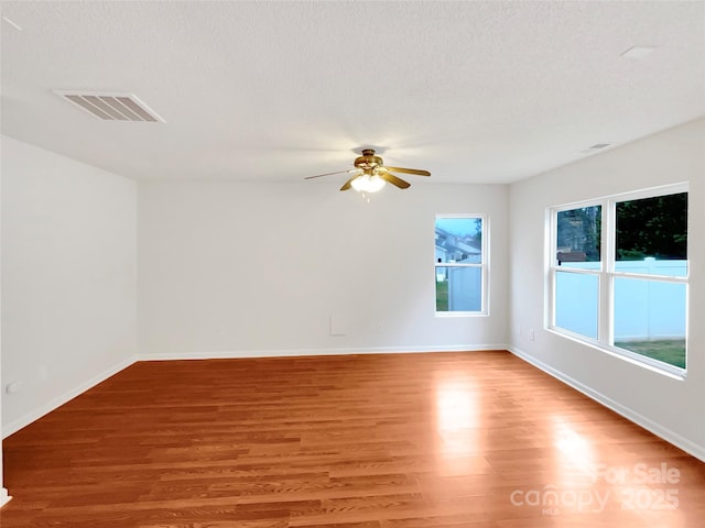 unfurnished room with baseboards, visible vents, light wood finished floors, ceiling fan, and a textured ceiling