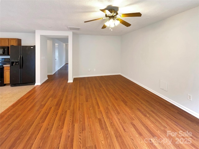 unfurnished living room with a ceiling fan, baseboards, visible vents, light wood finished floors, and a textured ceiling