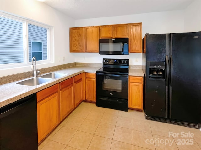 kitchen featuring light countertops, light tile patterned floors, brown cabinets, black appliances, and a sink