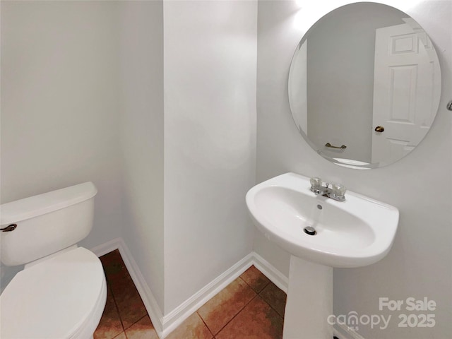 half bath featuring baseboards, toilet, and tile patterned flooring