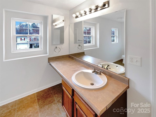 bathroom featuring toilet, vanity, and baseboards