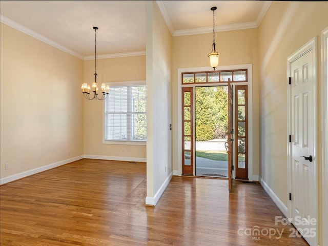 entryway with crown molding, a notable chandelier, and wood finished floors