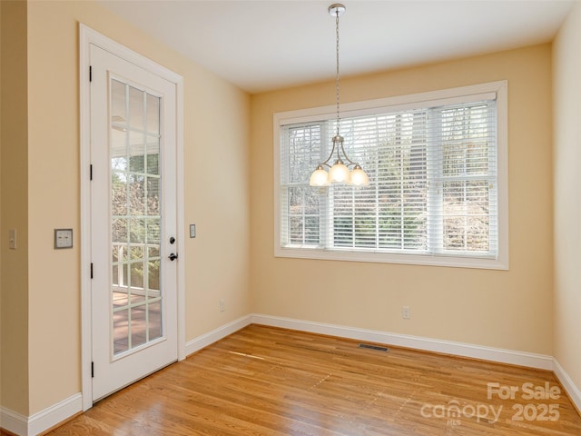 unfurnished dining area with visible vents, baseboards, light wood-style flooring, and a chandelier