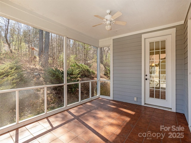 unfurnished sunroom with a ceiling fan and a healthy amount of sunlight