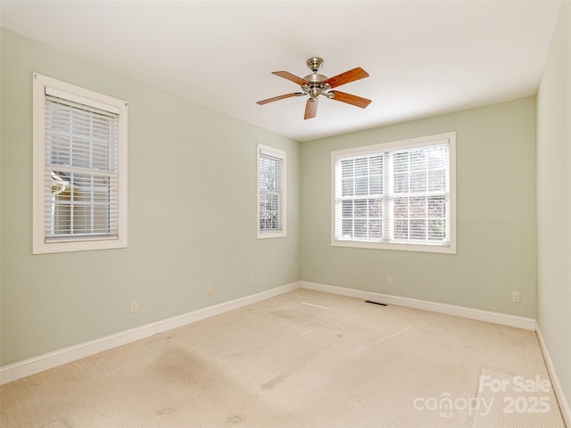 spare room featuring visible vents, light colored carpet, baseboards, and ceiling fan