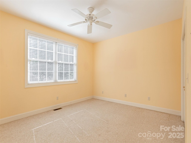 carpeted empty room featuring visible vents, baseboards, and ceiling fan