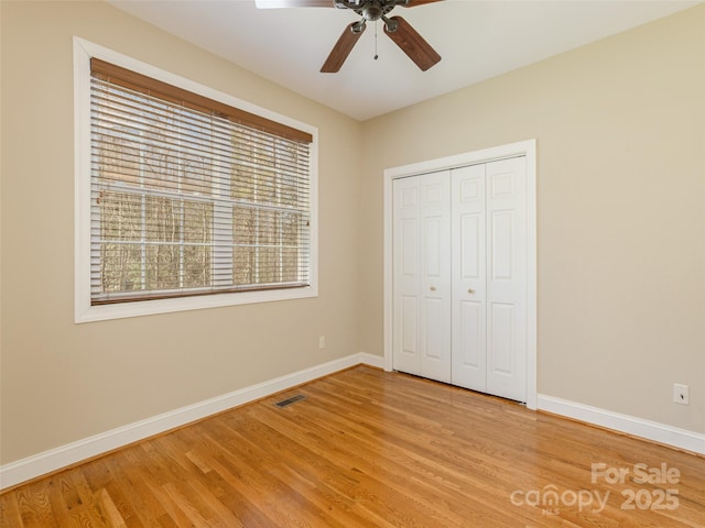 unfurnished bedroom with visible vents, baseboards, ceiling fan, light wood-style flooring, and a closet