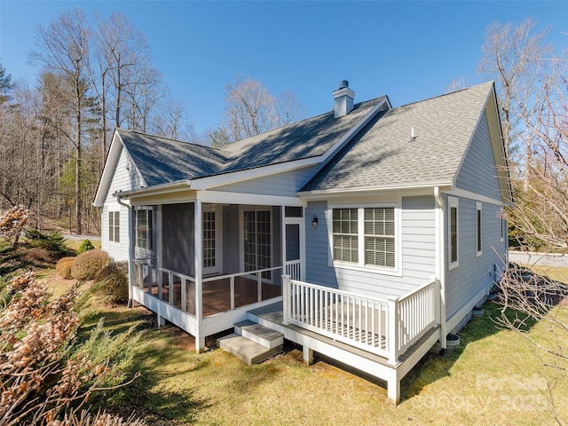 back of house with roof with shingles, a yard, a sunroom, and a chimney