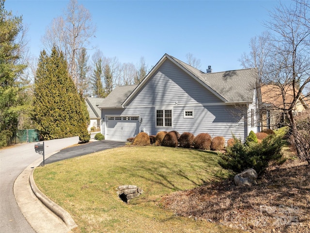 view of side of property with aphalt driveway, an attached garage, a shingled roof, and a yard