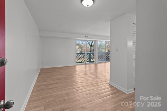 empty room featuring light wood-type flooring, baseboards, and visible vents