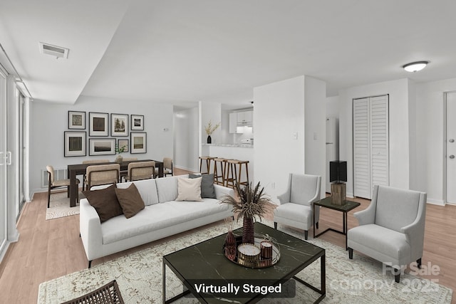 living room with light wood-style flooring, baseboards, and visible vents