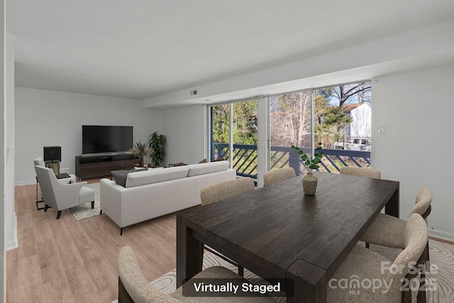 dining space featuring light wood-style flooring and baseboards