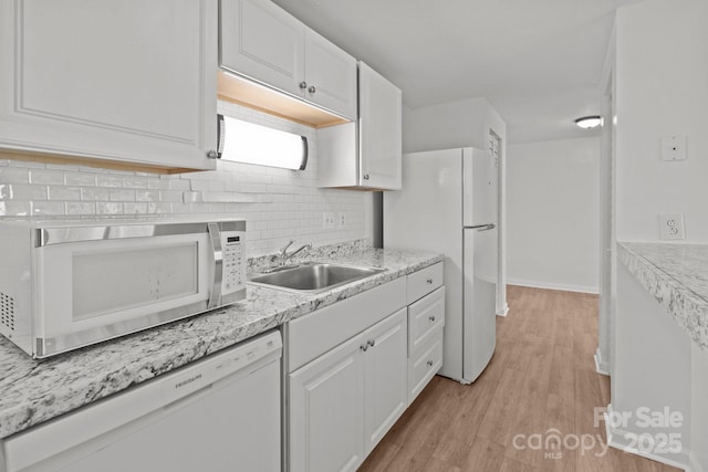 kitchen featuring white cabinets, white appliances, light countertops, and a sink