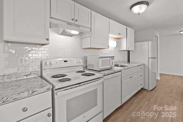 kitchen featuring white appliances, light wood finished floors, a sink, under cabinet range hood, and white cabinetry