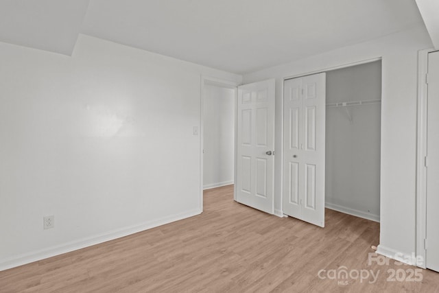 unfurnished bedroom with a closet, baseboards, and wood finished floors