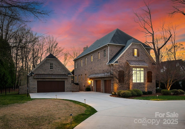 french country inspired facade with a yard, driveway, brick siding, and an attached garage