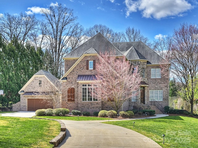 view of front facade with driveway, a standing seam roof, a front lawn, brick siding, and metal roof