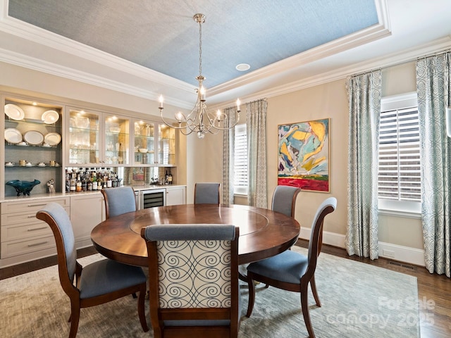 dining room featuring beverage cooler, a raised ceiling, baseboards, and wood finished floors