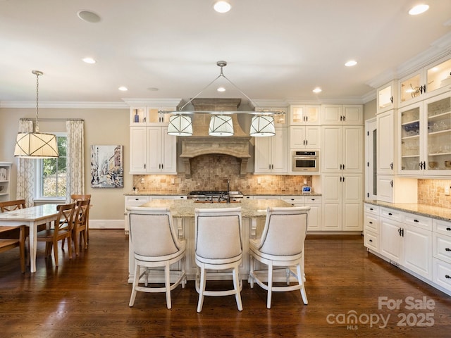 kitchen featuring light stone counters, backsplash, oven, and ornamental molding