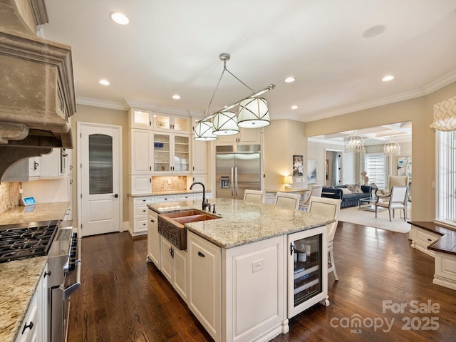 kitchen featuring high quality appliances, a sink, wine cooler, glass insert cabinets, and a notable chandelier