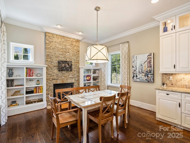 dining room featuring a fireplace, dark wood-style floors, baseboards, and ornamental molding