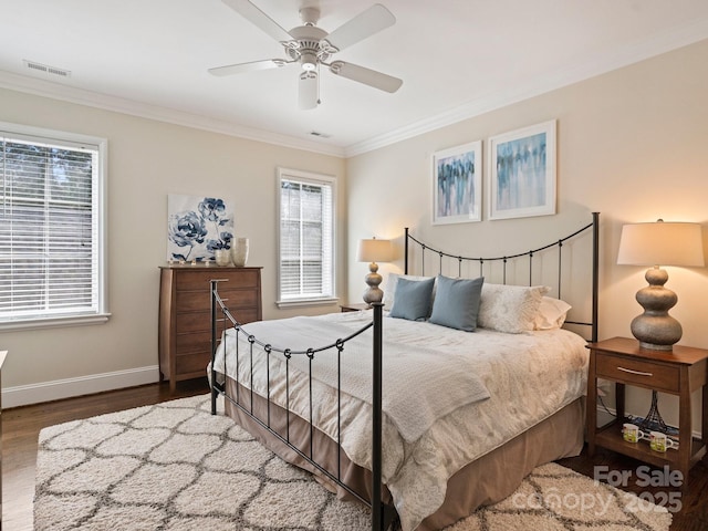 bedroom with baseboards, wood finished floors, visible vents, and ornamental molding