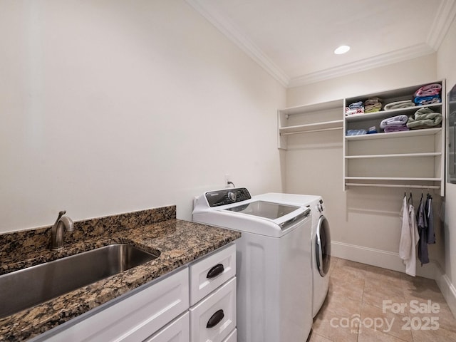 washroom with crown molding, baseboards, washing machine and dryer, cabinet space, and a sink