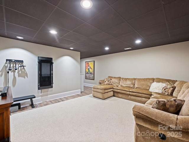 living area featuring wood finished floors, recessed lighting, baseboards, and a paneled ceiling