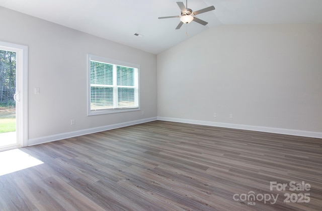 empty room featuring lofted ceiling, plenty of natural light, wood finished floors, and visible vents