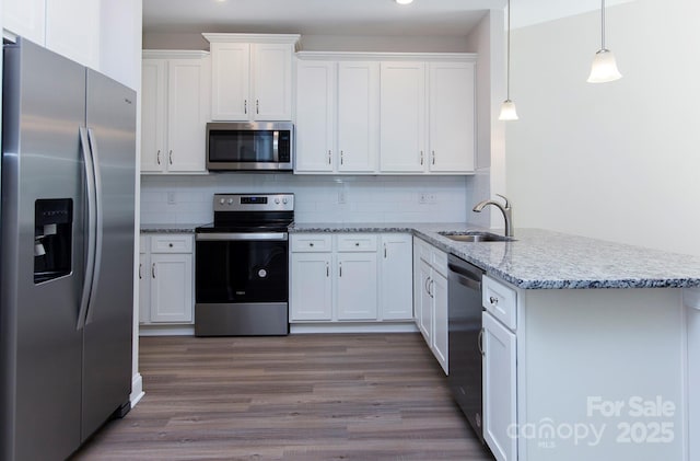 kitchen featuring stainless steel appliances, tasteful backsplash, a peninsula, and white cabinets