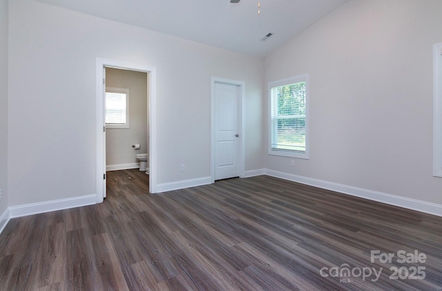 unfurnished bedroom with multiple windows, baseboards, dark wood-type flooring, and lofted ceiling