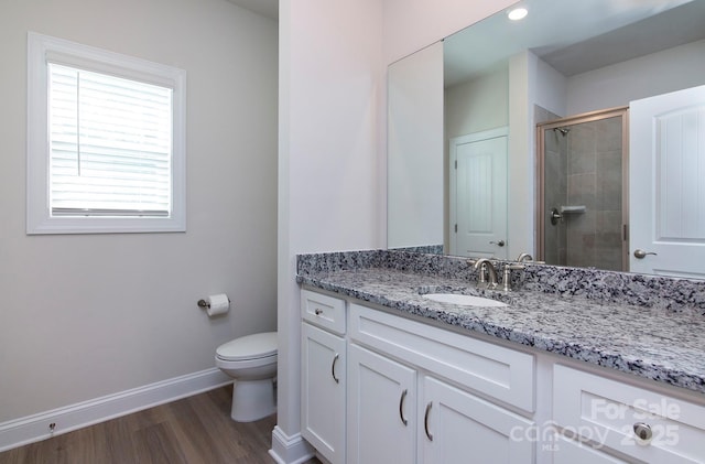 bathroom featuring vanity, wood finished floors, baseboards, a shower stall, and toilet