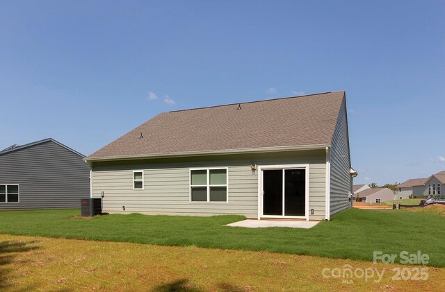 back of house featuring cooling unit, a lawn, and roof with shingles