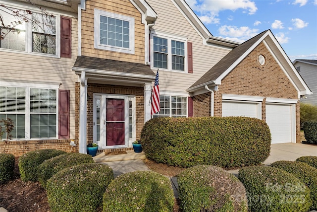 view of front of house featuring concrete driveway, an attached garage, and brick siding