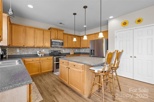 kitchen featuring tasteful backsplash, visible vents, a center island, stainless steel appliances, and a sink