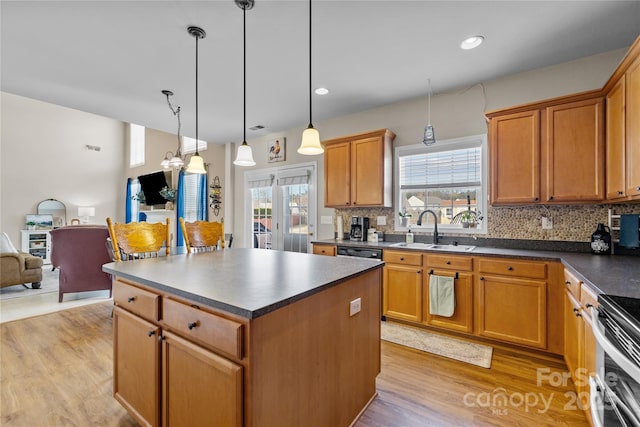 kitchen with light wood-type flooring, a sink, dark countertops, open floor plan, and decorative backsplash